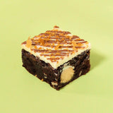 Bueno Brownie with hazelnut filling, white chocolate topping, and crunchy fuilletine pieces on a green background.